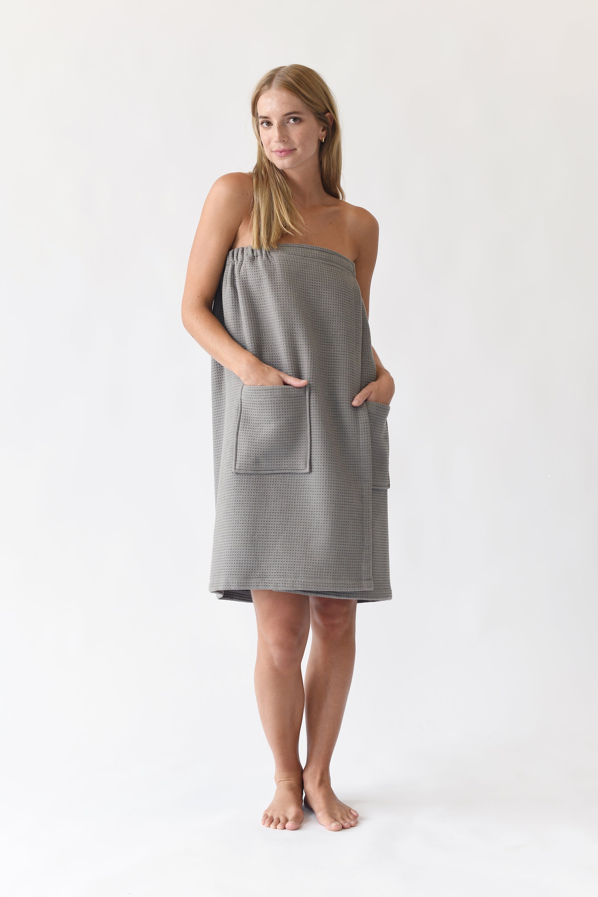 Charcoal Waffle Bath Wrap. The bath wrap is shown being worn by a woman. Photo was taken with a white background.|Color:Charcoal