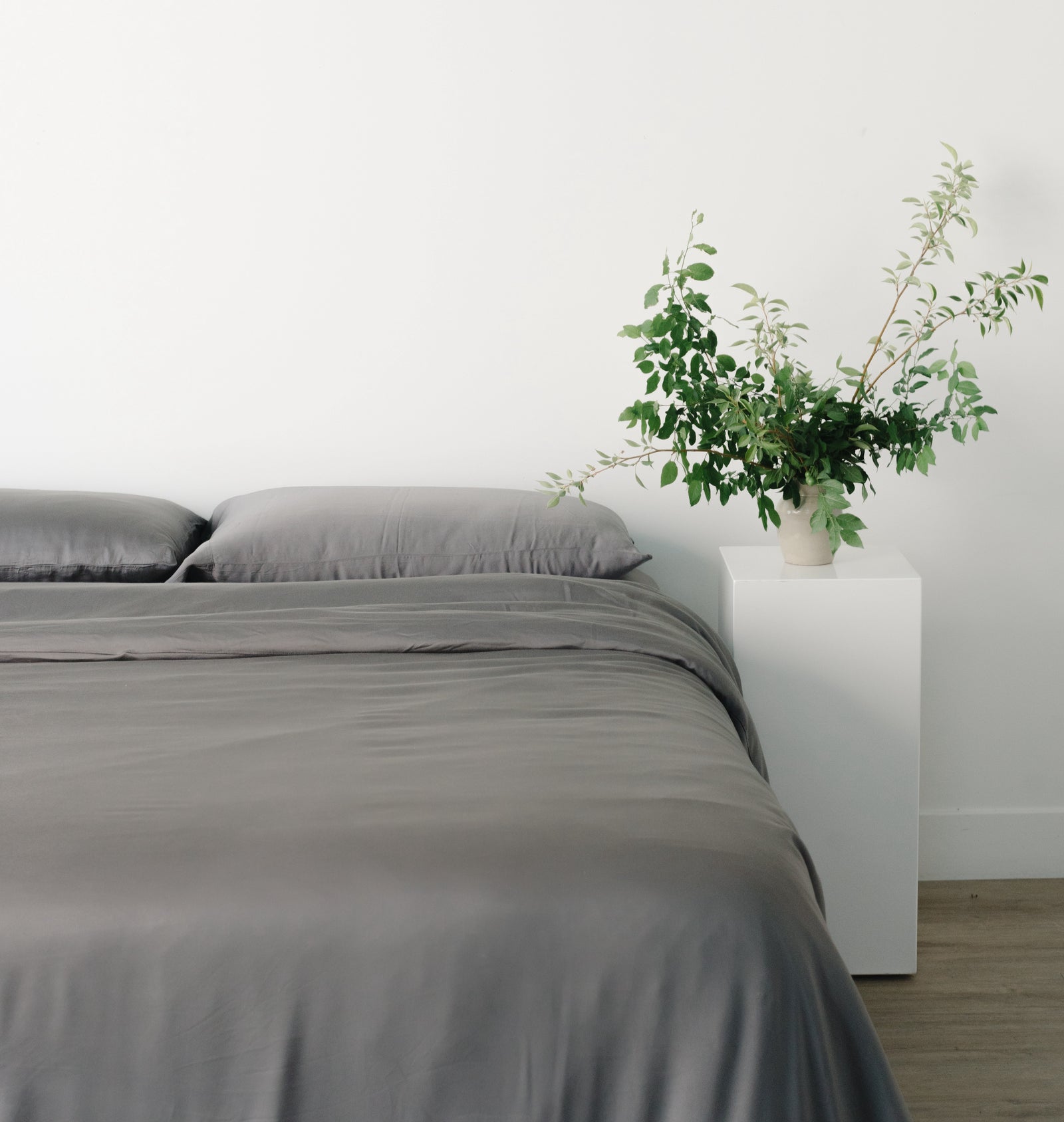 Charcoal bedding on bed in room with white walls 