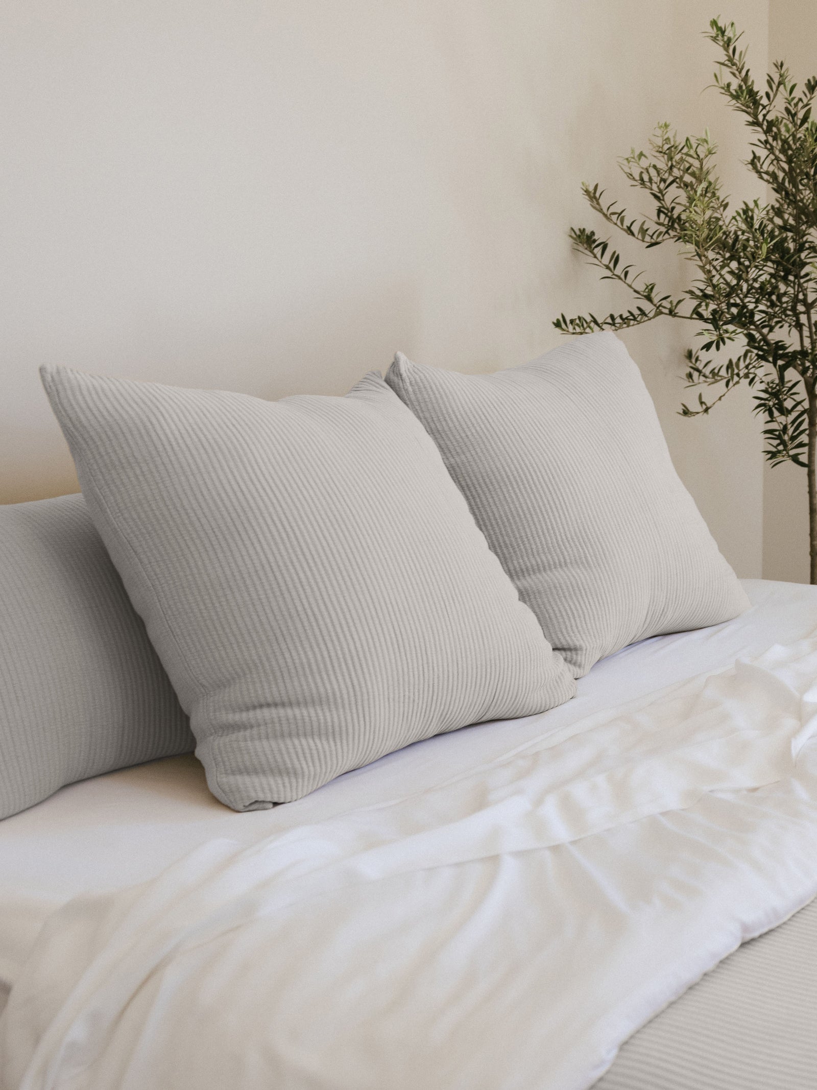 Light Grey coverlet shams on white bed 