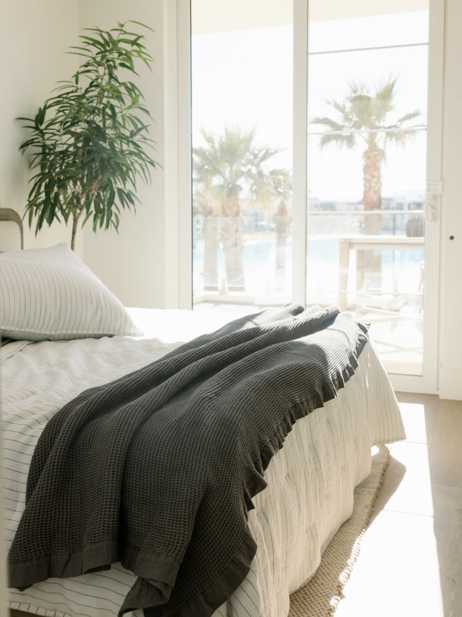 Sun shining on bed with charcoal pencil stripe quilt and shams 