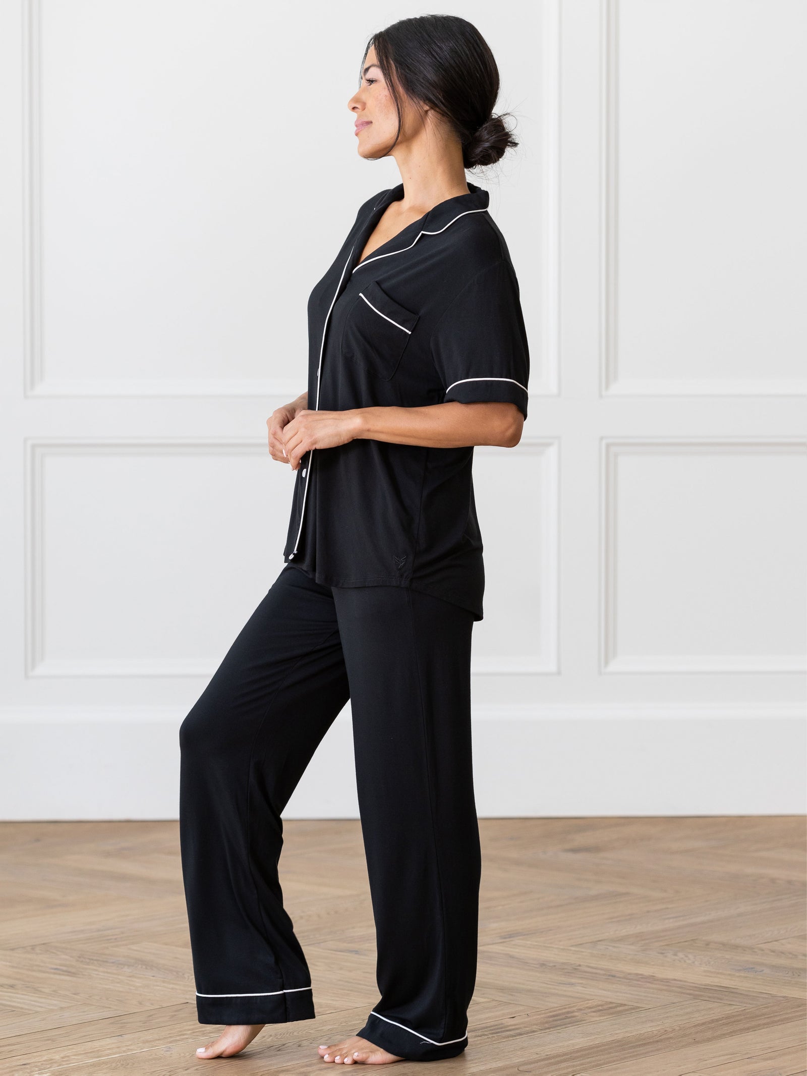 Black Short Sleeve & Pant Bamboo Pajama Set modeled by a woman. The photo was taken in a high contrast setting, showing off the colors and lines of the pajamas. 