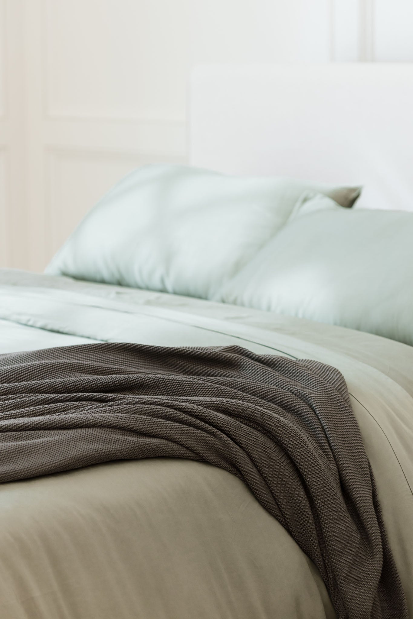 Charcoal cloud knit blanket sitting on bed 