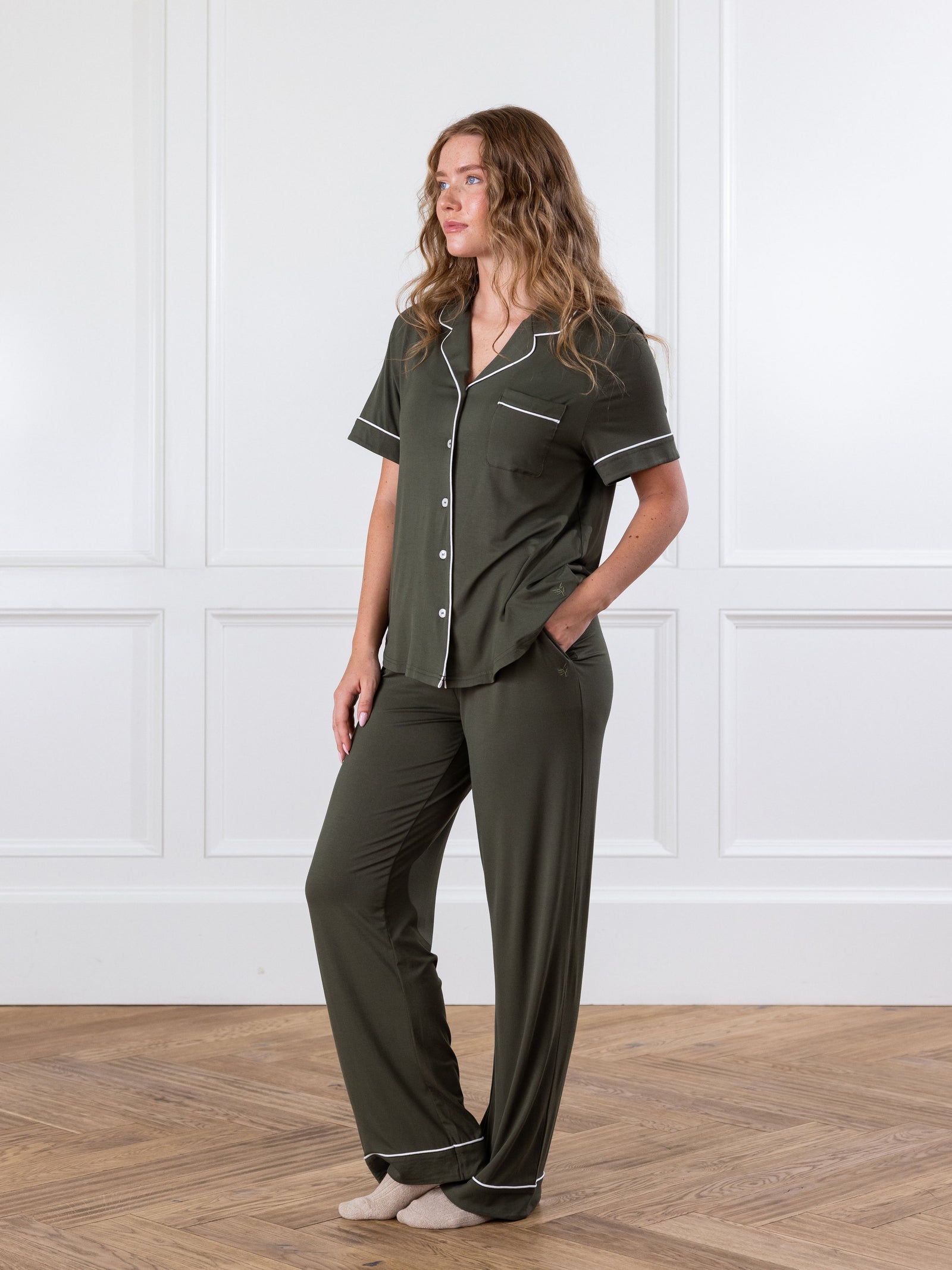 Olive Short Sleeve & Pant Bamboo Pajama Set modeled by a woman. The photo was taken in a high contrast setting, showing off the colors and lines of the pajamas. 