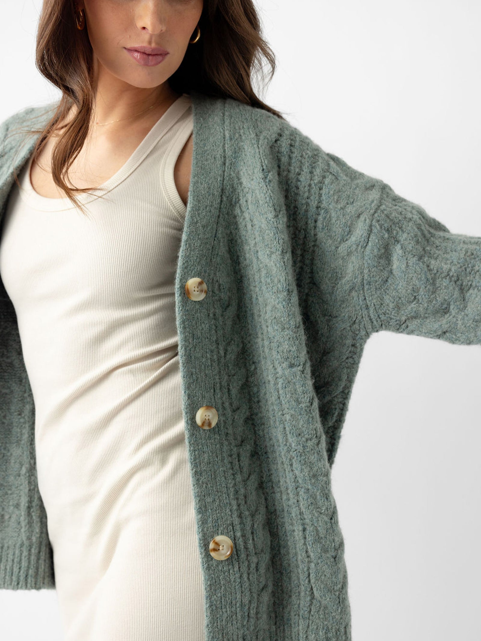 Close up of woman wearing thyme cardigan over off-white dress 