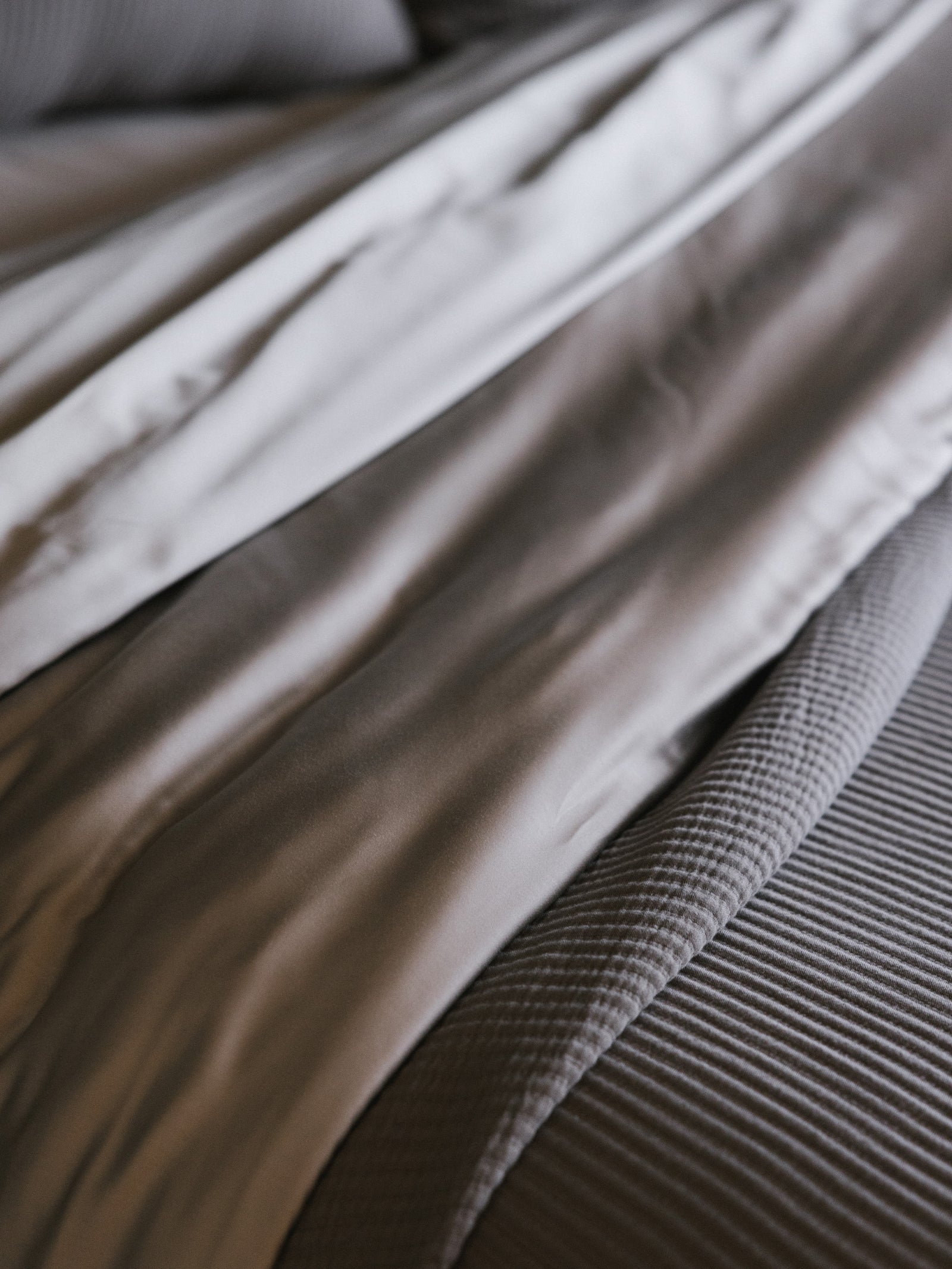 Close up of dove grey sheet and coverlet 