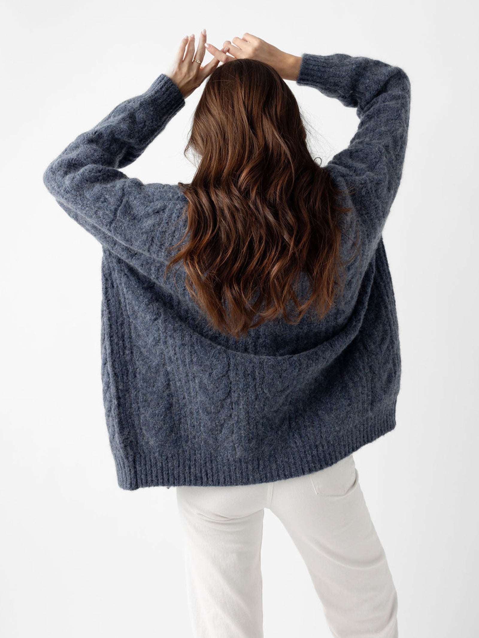 Back of woman wearing indigo cardigan with white background 