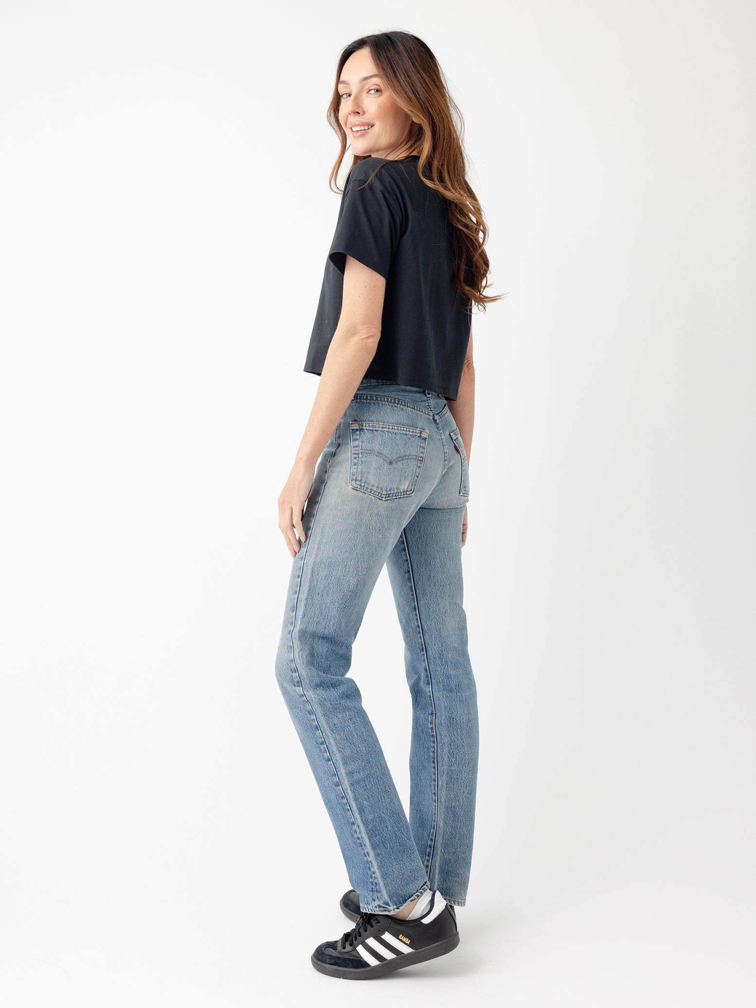 Jet Black All Day Cropped Tee. The photo of the All Day Cropped Tee is taken with a with a white background and is worn by a woman. 