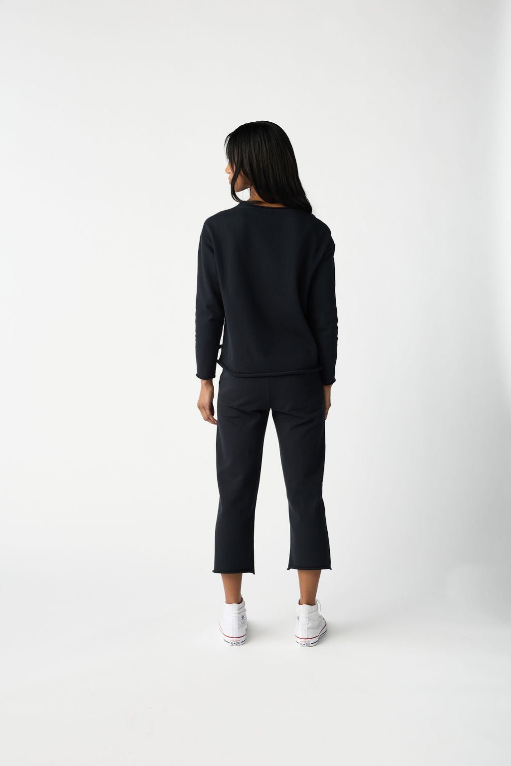 A dark haired woman wears Cozy Earth Women's Chelsea Pullover in Jet Black.  She is pictured from behind. 