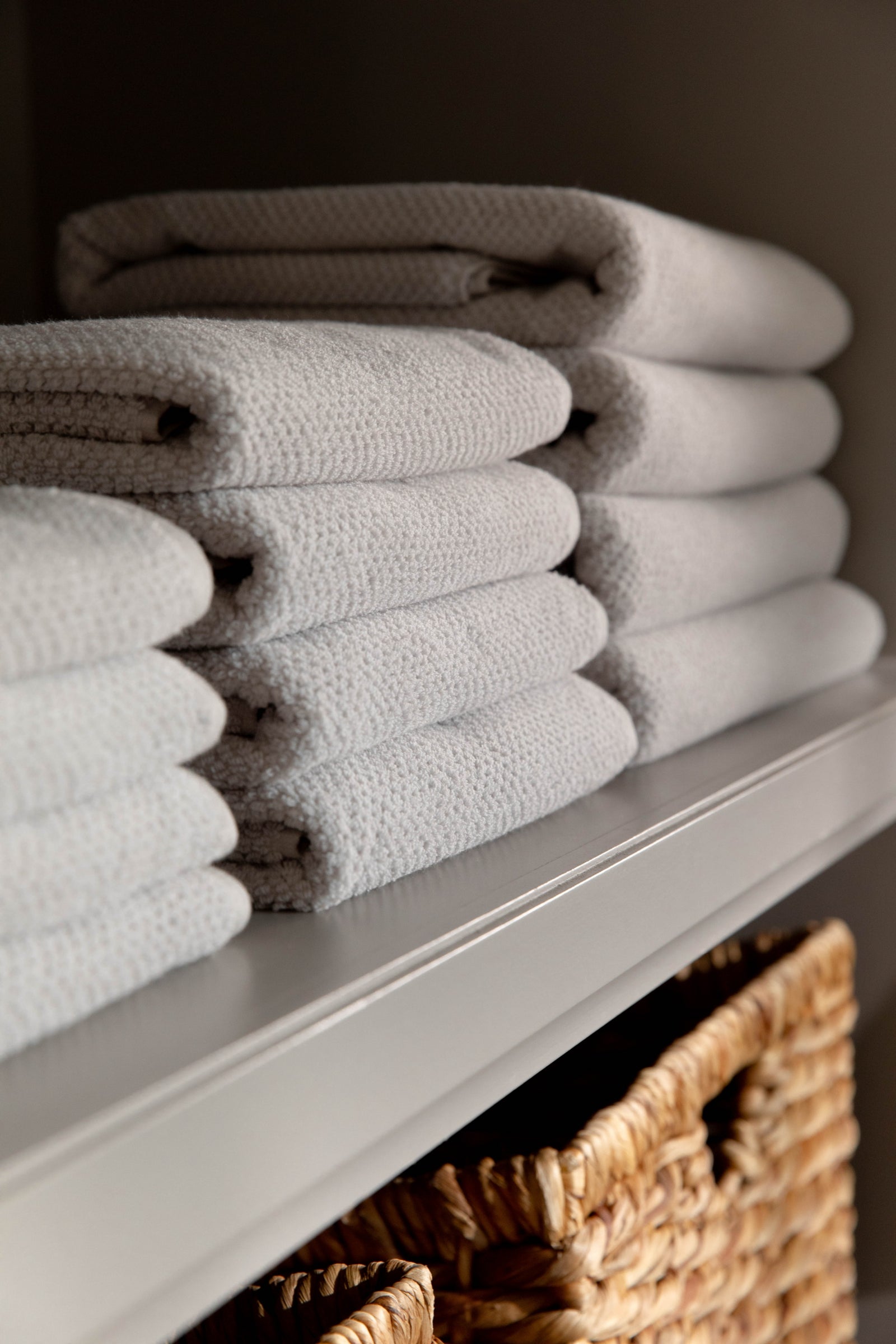 Complete Nantucket Bath Bundle in the color Heathered Light Grey. Photo of Complete Nantucket Bath Bundle taken as the towels rest on a shelf in a bathroom. 