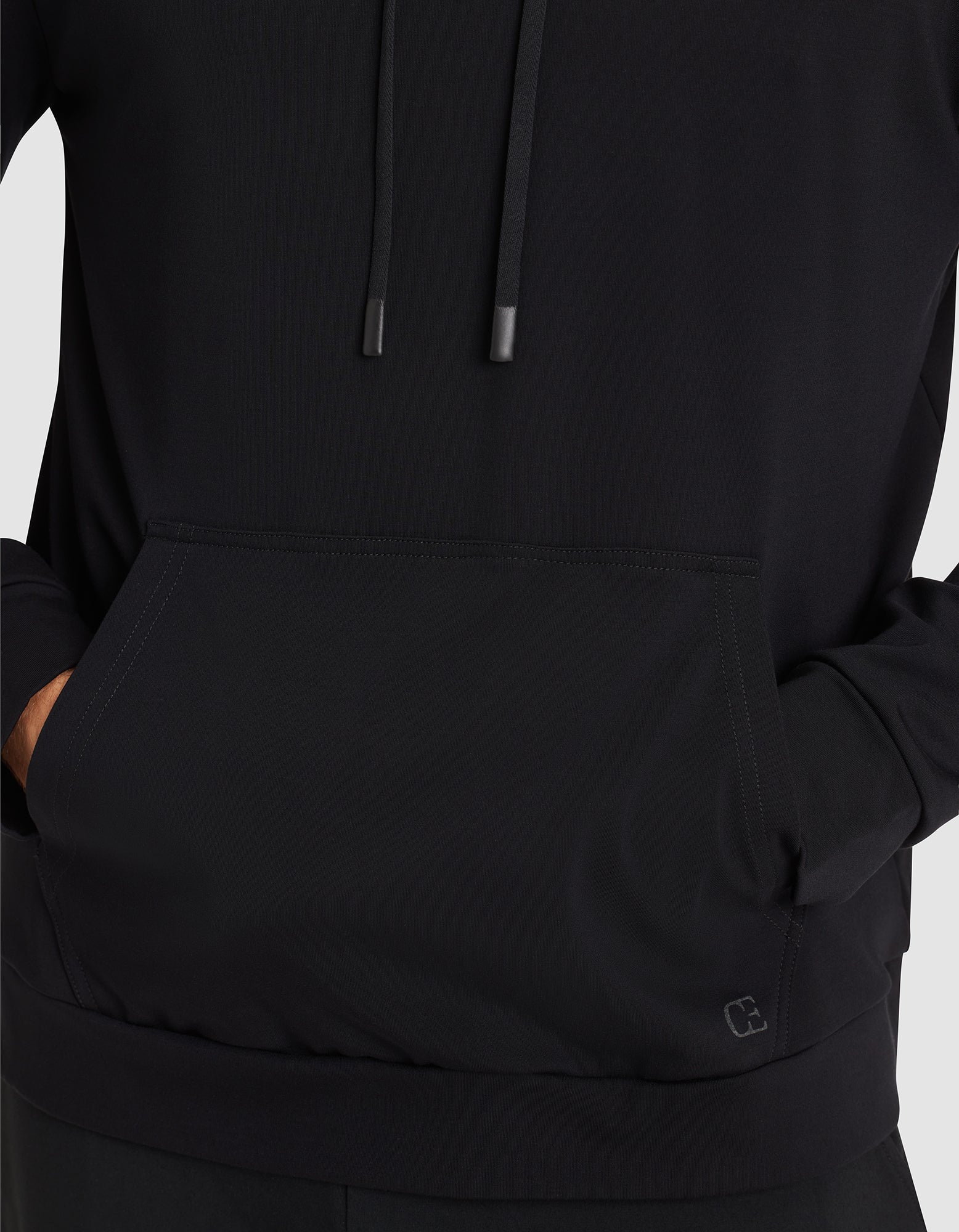 A person wearing the Cozy Earth Men's Brushed Bamboo Hoodie, featuring a front pocket and drawstrings, stands with hands partially in the pocket against a plain light background. 