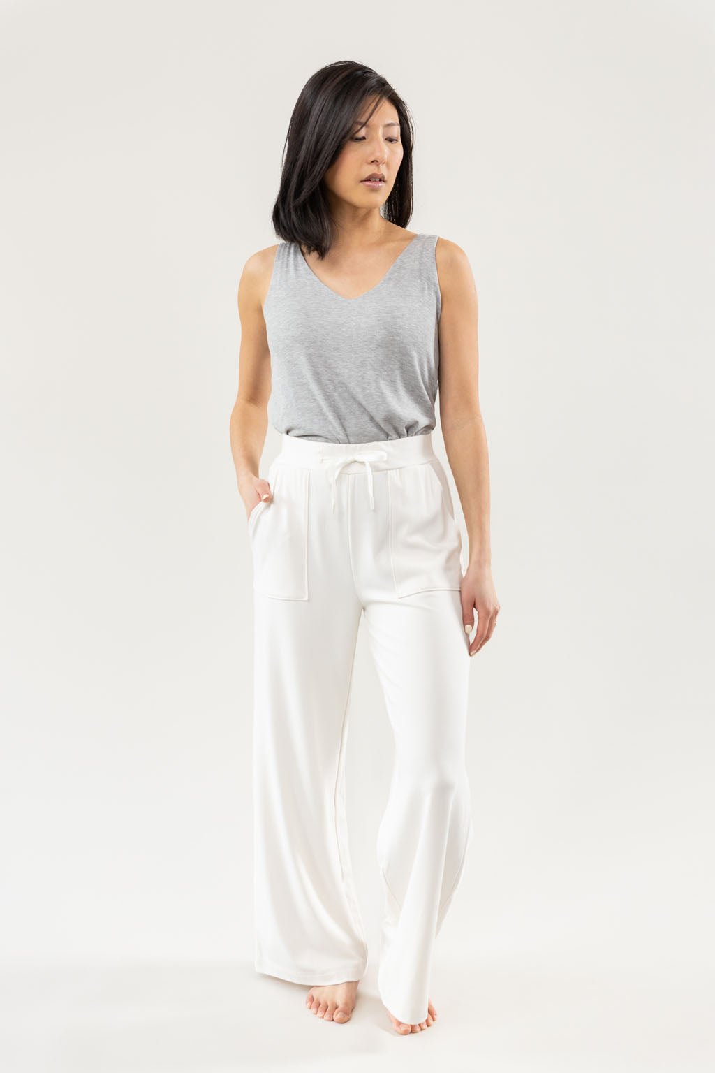 Ivory Bamboo Wide Leg Patch Pocket Pant modeled by a woman. The photo was taken in a high contrast setting, showing off the colors and lines of the pajamas. |Color: Ivory