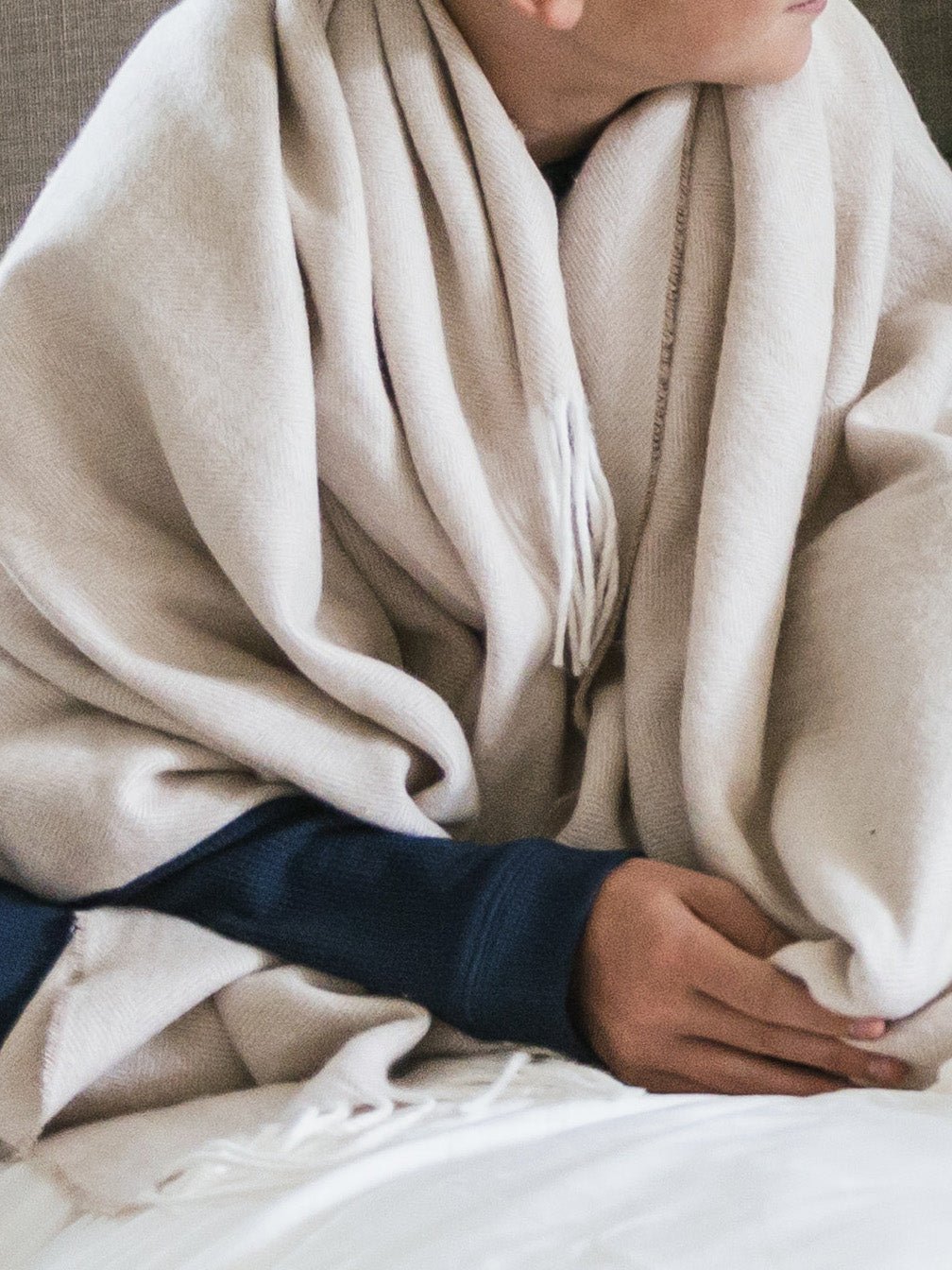 Person sitting with oatmeal throw wrapped around them 