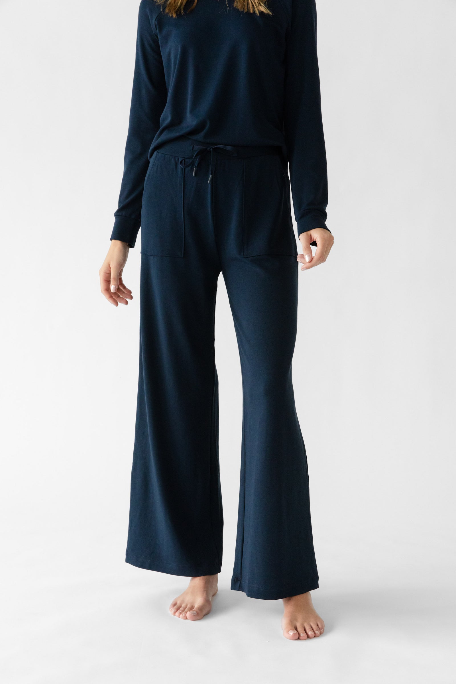 Navy Bamboo Wide Leg Patch Pocket Pant modeled by a woman. The photo was taken in a high contrast setting, showing off the colors and lines of the pajamas. 