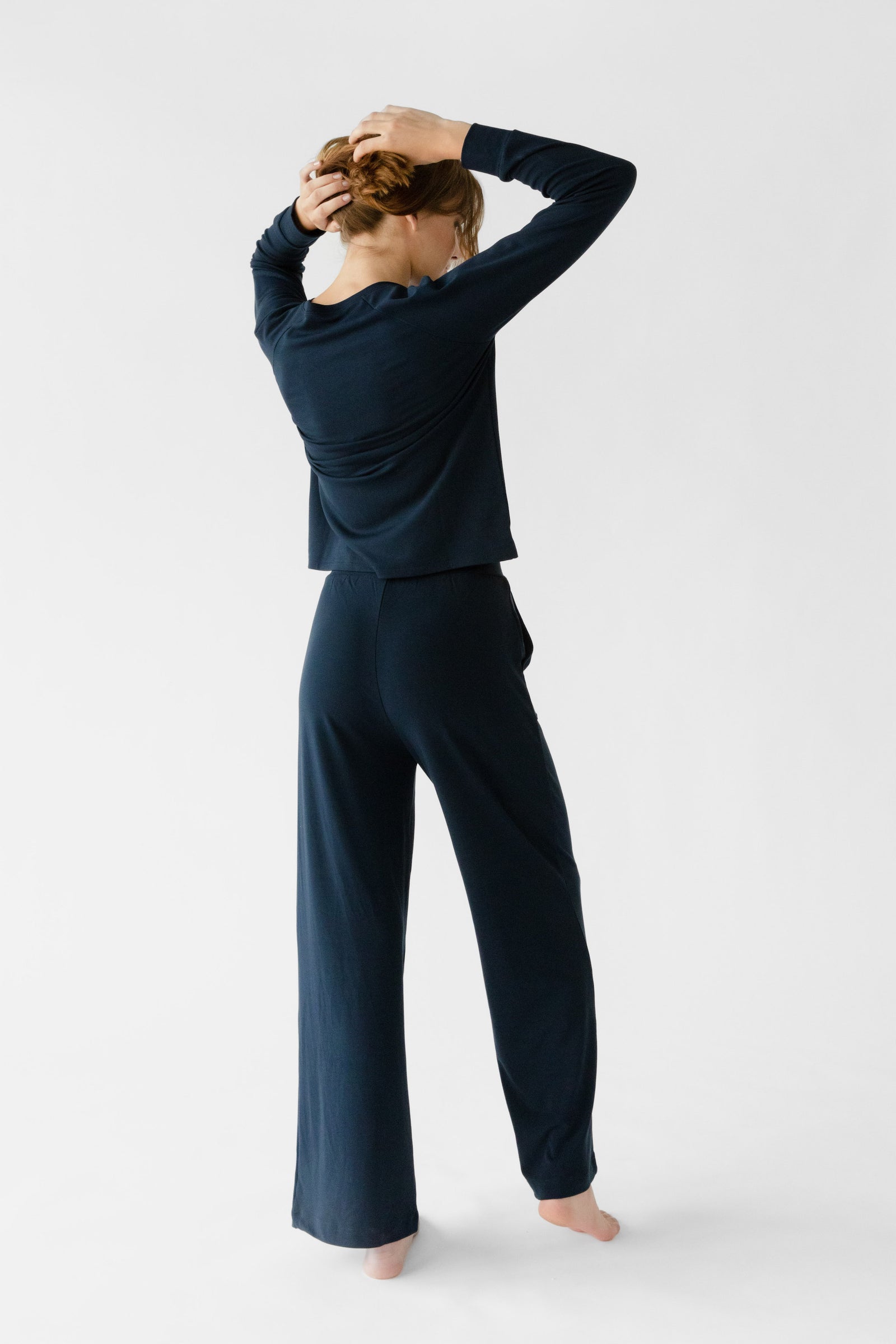 Navy Bamboo Wide Leg Patch Pocket Pant modeled by a woman. The photo was taken in a high contrast setting, showing off the colors and lines of the pajamas. 