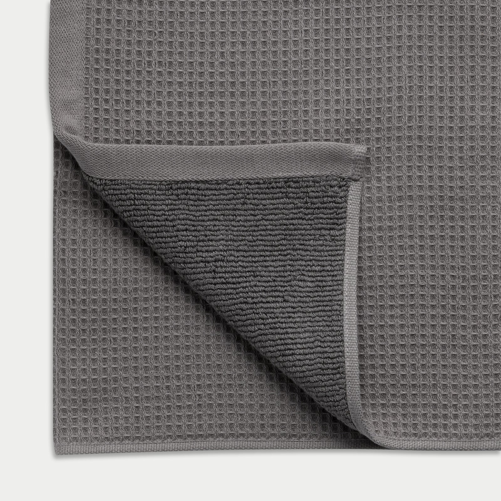 Waffle Bath Towel in the color Charcoal. Photo of Waffle Bath Towel taken close up showing the corner of the towel 