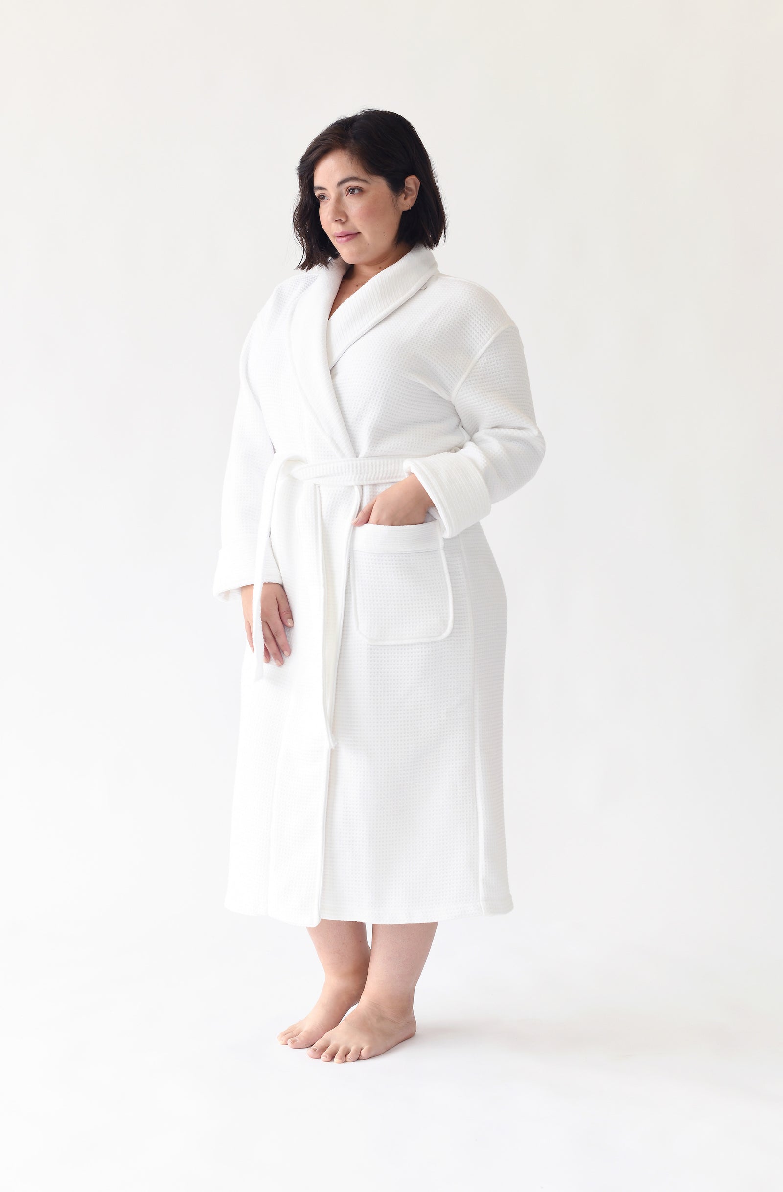 Woman wearing Bamboo Waffle Bath robe standing in front of a with a white background. 